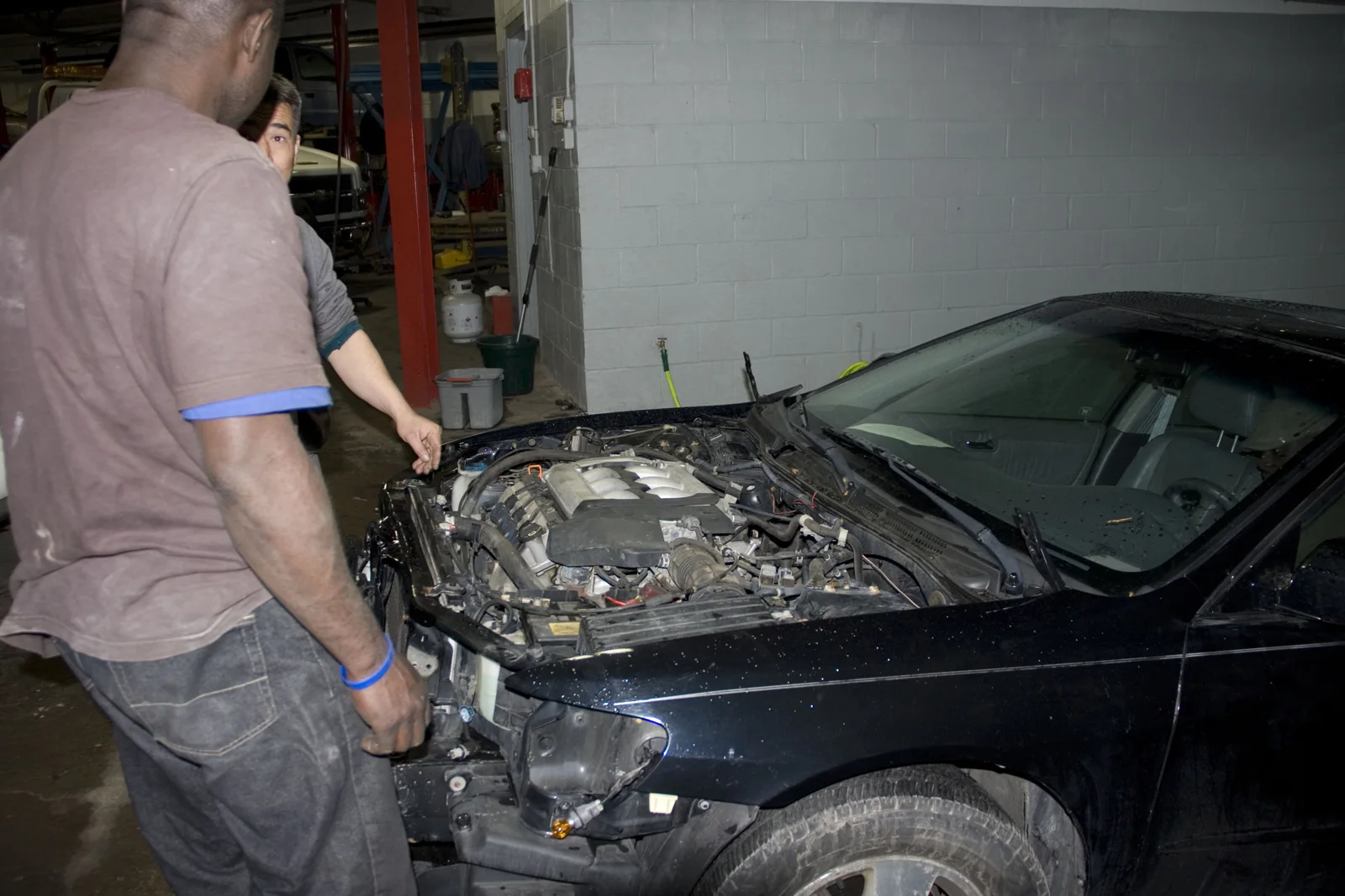 A mechanic beside an open engine bay inside Lanhart's shop